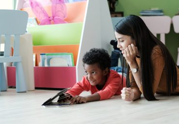 Young asian woman teacher and African boy in kindergarten classroom, preschool education concept